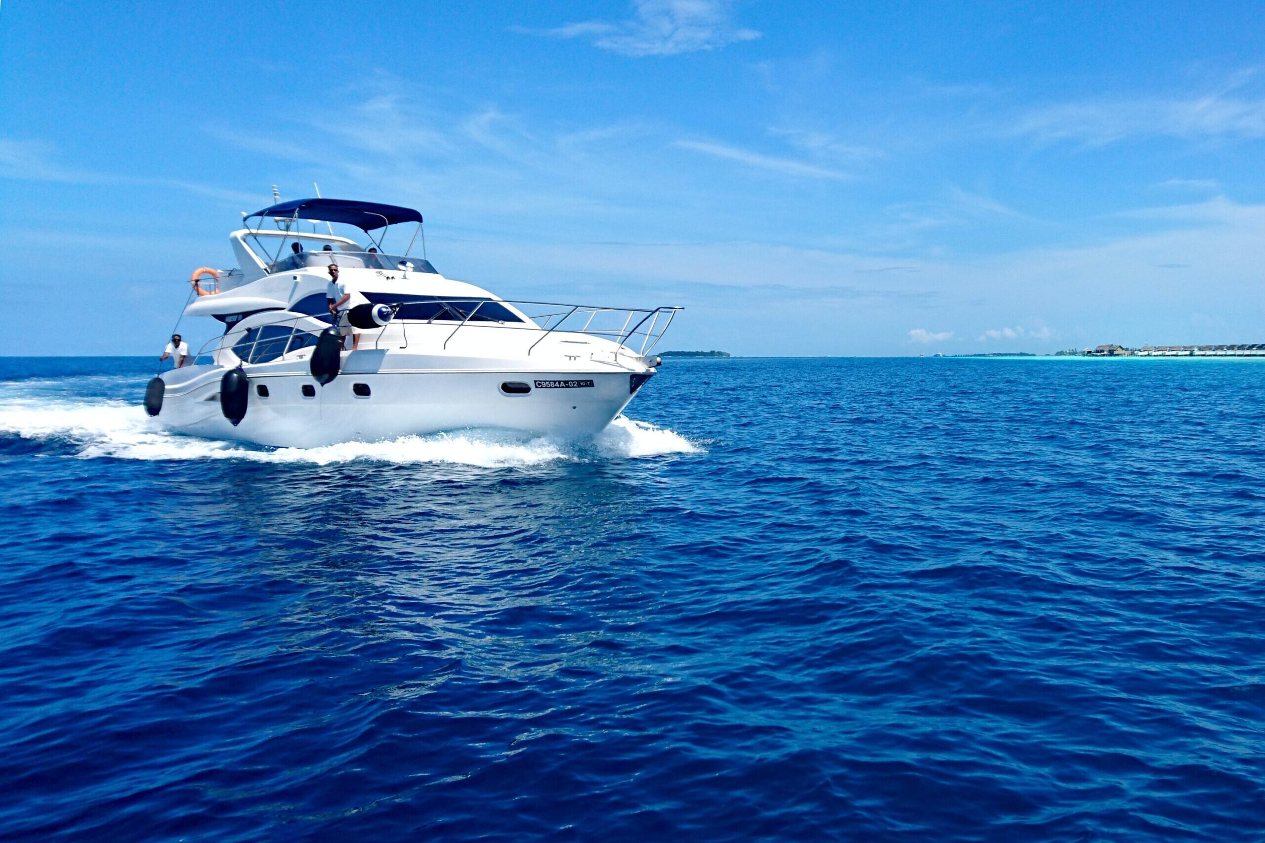 White yacht on blue ocean under clear sky with people aboard.